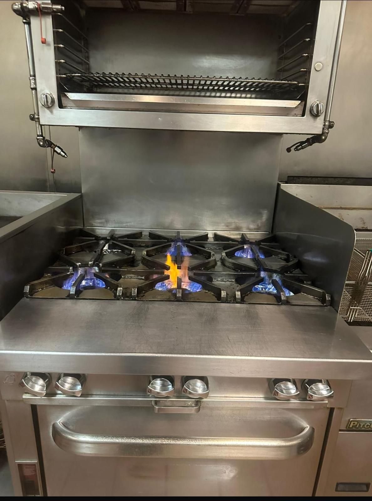 Commercial range with burners lit after a service clean